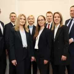 Grupa profesjonalistów w garniturach pozuje do zdjęcia.
