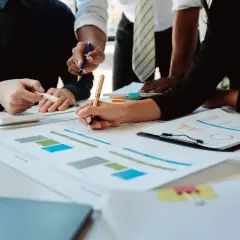 Zespół analizuje dokumenty i wykresy na stole.