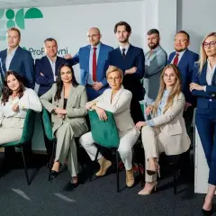 Zespół prawników w eleganckich garniturach pozuje do zdjęcia.