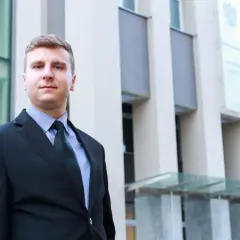 Mężczyzna w garniturze przed nowoczesnym budynkiem.