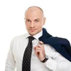 Łysy mężczyzna w białej koszuli i krawacie, z marynarką na ramieniu.