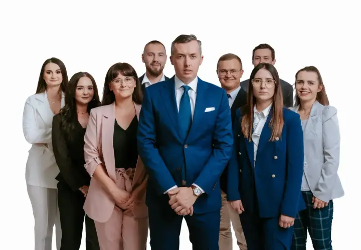 Grupa profesjonalistów w garniturach i kostiumach, stojąca przed białym tłem.
