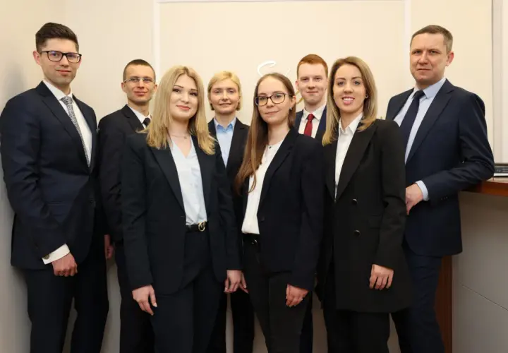 Grupa profesjonalistów w garniturach pozuje do zdjęcia.