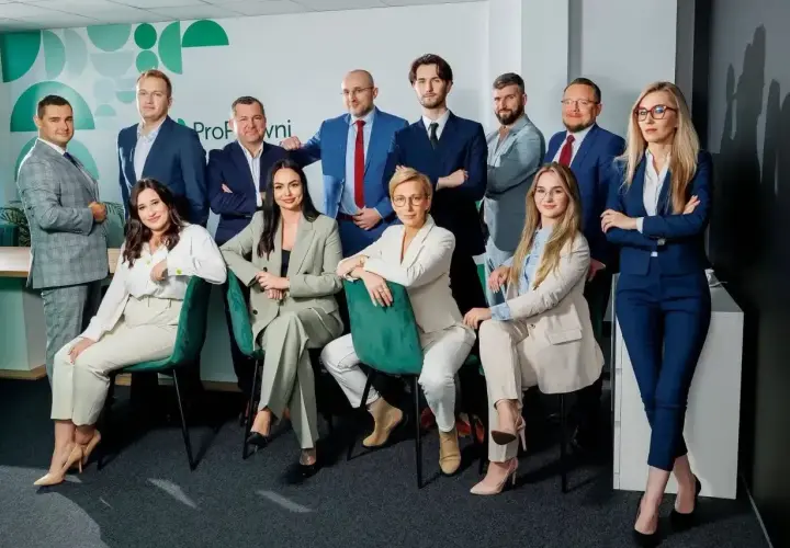 Zespół prawników w eleganckich garniturach pozuje do zdjęcia.