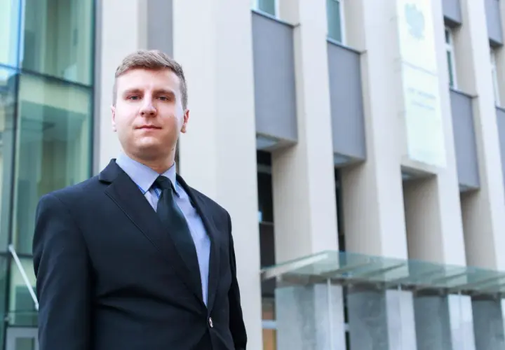 Mężczyzna w garniturze przed nowoczesnym budynkiem.