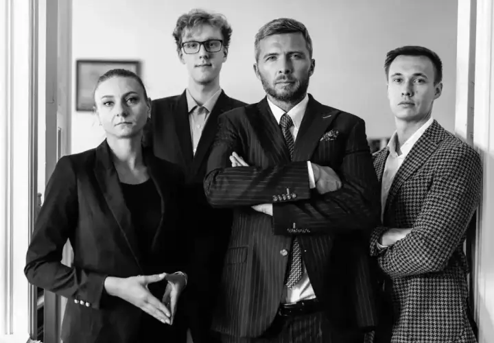Cztery osoby w garniturach stojące w rzędzie, dwie kobiety i dwóch mężczyzn.