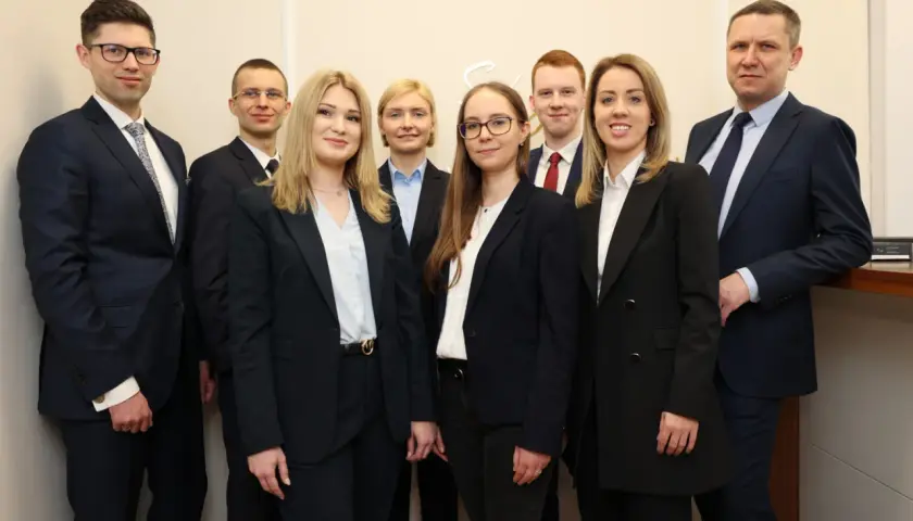 Grupa profesjonalistów w garniturach pozuje do zdjęcia.