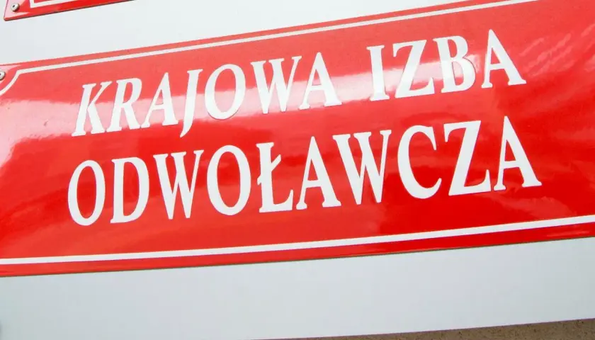 Czerwona tablica z białym napisem "KRAJOWA IZBA ODWOŁAWCZA".