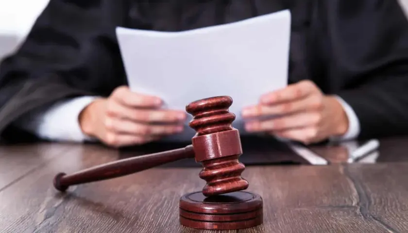 Sędzia w todze czyta dokumenty. Obok młotek sędziowski. Zastanawiasz się, ile czasu ma sąd na dostarczenie wyroku w sprawie karnej?