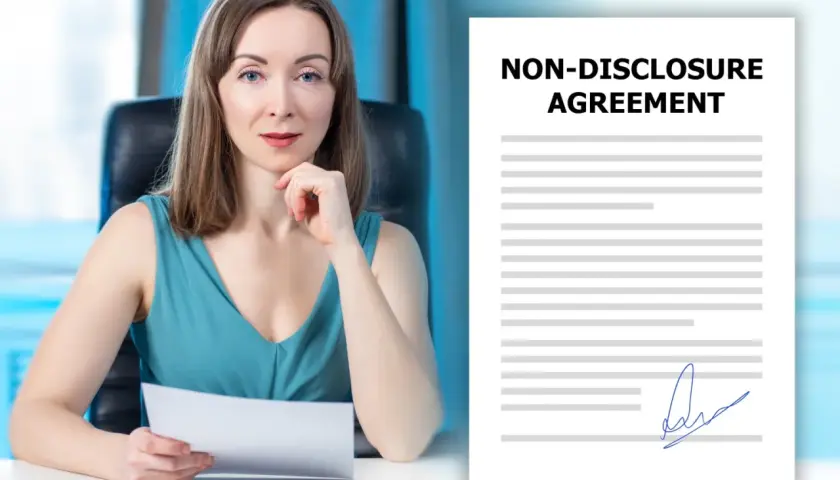 Kobieta w biurze trzyma dokument. Obok widoczny jest podpisany dokument "Non-Disclosure Agreement", czyli umowa o zachowanie poufności.