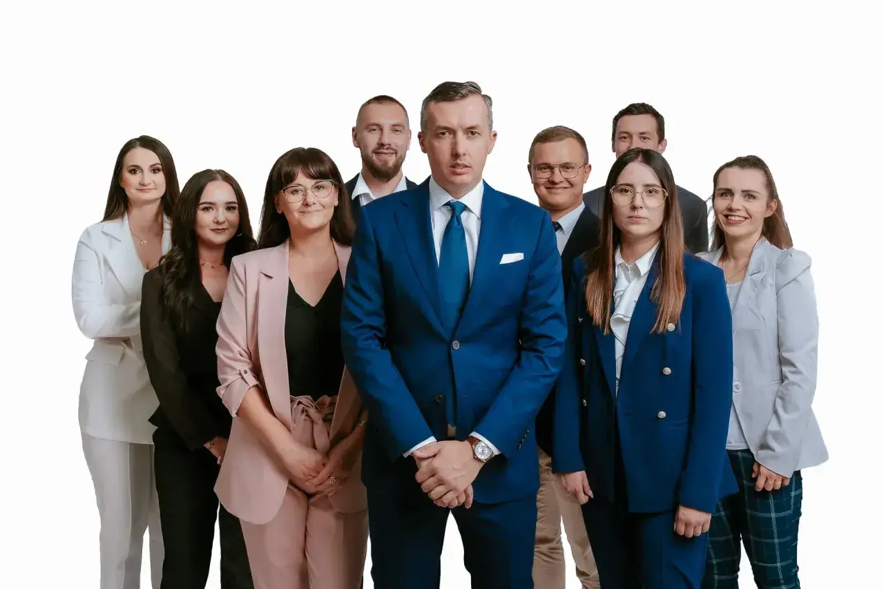 Grupa profesjonalistów w garniturach i kostiumach, stojąca przed białym tłem.