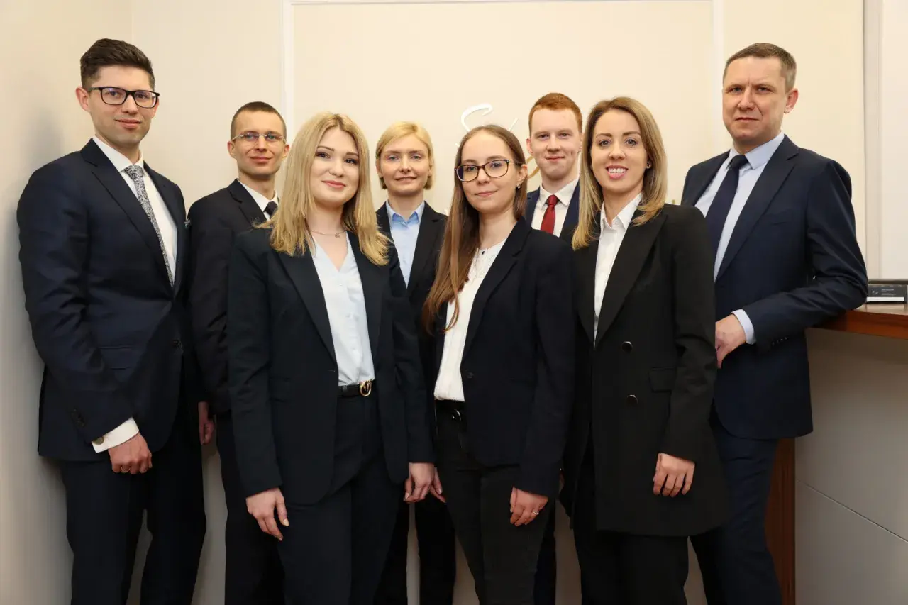 Grupa profesjonalistów w garniturach pozuje do zdjęcia.