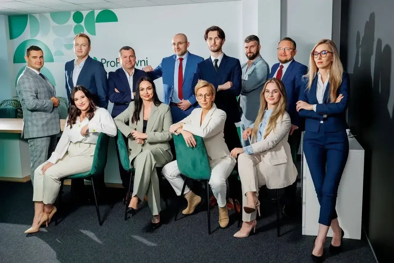 Zespół prawników w eleganckich garniturach pozuje do zdjęcia.
