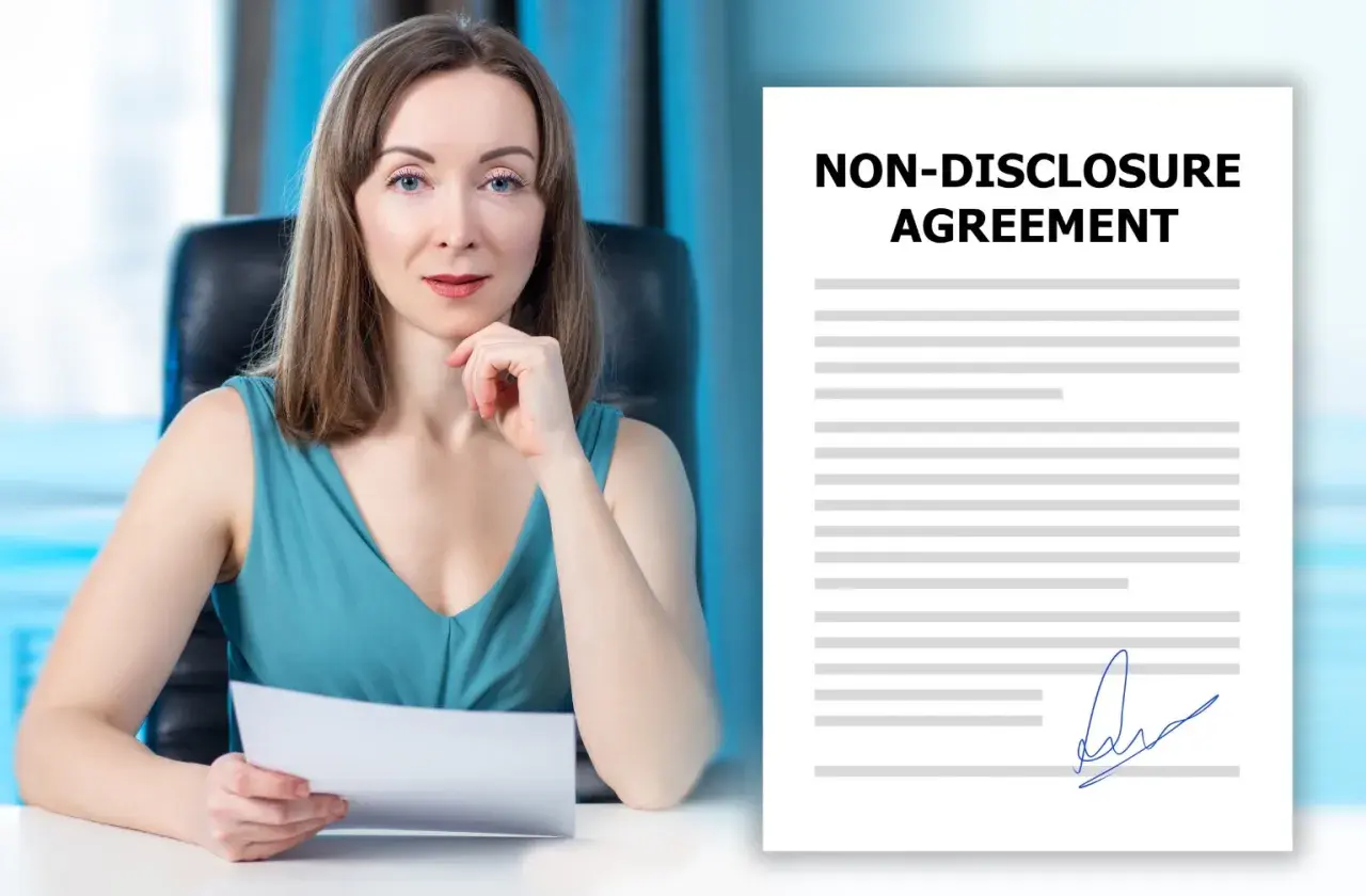 Kobieta w biurze trzyma dokument. Obok widoczny jest podpisany dokument "Non-Disclosure Agreement", czyli umowa o zachowanie poufności.